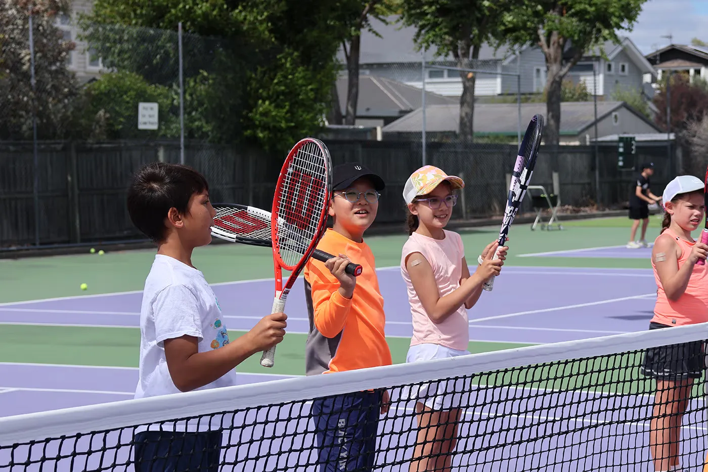 A group of junior tennis players enjoying a coaching session at the Waimairi Tennis Club