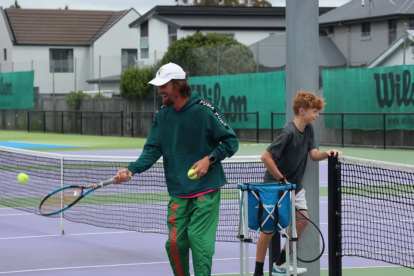 A coach and a junior player on court at the Waimairi Tennis Club have a fun session hitting tennis balls