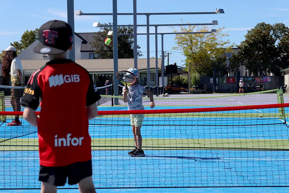 2 young junior players hitting tennis balls during a Hot Shots tennis lesson